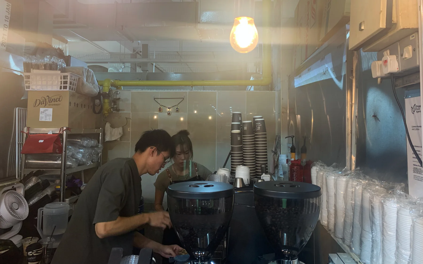 Two of the Daylight Coffee team working the grinders and espresso machine inside the Amoy Street stall
